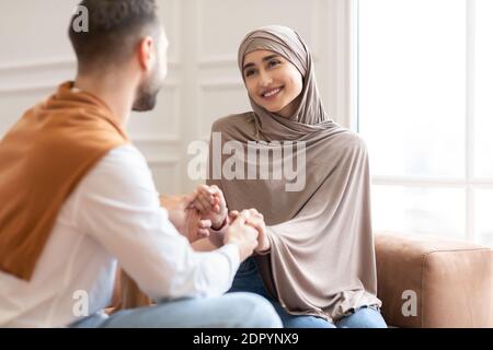 Liebende Muslimische Paar Hände Halten Sitzen Auf Couch Zu Hause Stockfoto