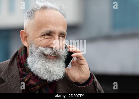 Nahaufnahme eines fröhlichen älteren Mannes, der am Telefon sprach Stockfoto