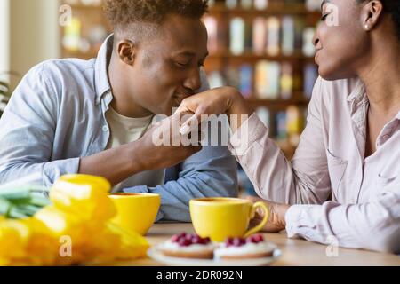 Romantischer junger Mann küsst seine geliebte Frau die Hand auf festliche Valentine's Dinner im gemütlichen Cafe Stockfoto