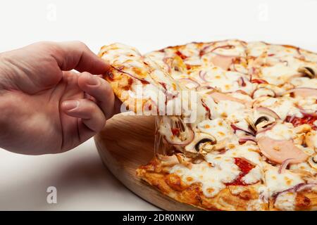 Die Hand des Mannes nimmt ein köstliches Stück Pizza mit Margarita oder Margarita mit Mozzarella, EIN Mann nimmt ein Stück italienische Pizza und zieht einen appetitlich geschmolzenen Käse. Stockfoto