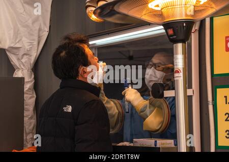 Seoul, Südkorea. Dezember 2020. Ein medizinisches Personal, das einen persönlichen Schutzanzug (PSA) trägt, nimmt eine Abstrichprobe von einem Mann an einer temporären COVID-19-Teststelle am Seoul Square. Südkorea erreichte 1,097 neue bestätigte COVID19-Fälle, was der höchste Rekord seit Ausbruch des Virus in Südkorea ist. Kredit: SOPA Images Limited/Alamy Live Nachrichten Stockfoto