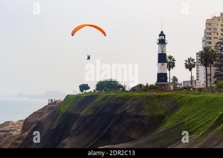 Lima, Peru - 19. Juni 2015: Gleitschirme segeln vor den Klippen von Miraflores in der Nähe des La Marina Leuchtturms über den Pazifik. Stockfoto