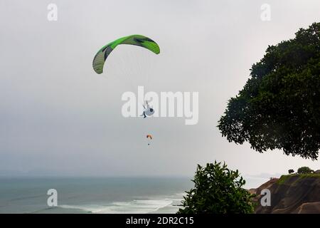 Lima, Peru - 19. Juni 2015: Gleitschirmflieger segeln vor den Klippen von Miraflores über den Pazifischen Ozean. Stockfoto