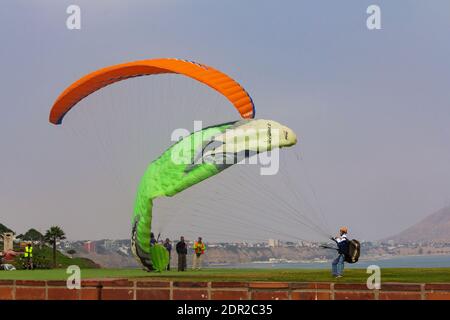 Lima, Peru - 19. Juni 2015: Gleitschirmflieger segeln vor den Klippen von Miraflores über den Pazifischen Ozean. Stockfoto