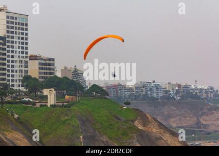 Lima, Peru - 19. Juni 2015: Gleitschirmflieger segeln vor den Klippen von Miraflores über den Pazifischen Ozean. Stockfoto