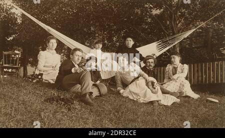 Antike c1905 Fotografie, Familienportrait auf Rasen mit Hängematte. Standort unbekannt, wahrscheinlich Neuengland. QUELLE: ORIGINALFOTO Stockfoto