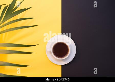 Draufsicht Bild von Kaffeetasse auf gelb und schwarz Hintergrund mit Grün. Flach liegend. Speicherplatz kopieren Stockfoto