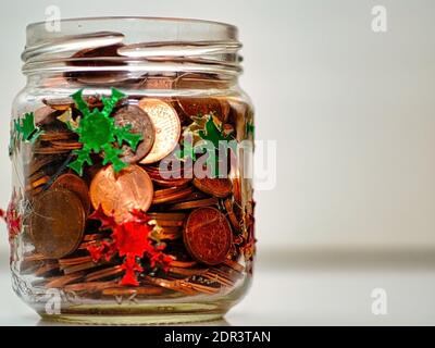 Eine Nahaufnahme von einem Glas gefüllt mit Münzen und Weihnachtsdekoration - sparen Sie sich für den Urlaub Stockfoto