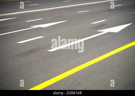 Richtungspfeile und Linien auf einer asphaltierten Straße. Stockfoto