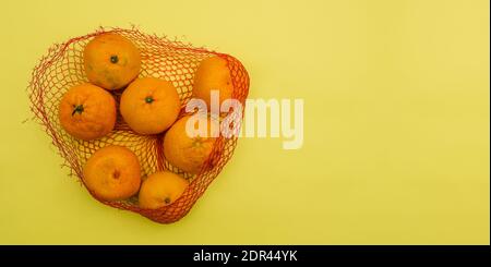 Mandarinen in einem offenen Paket, isoliert auf einem gelben Hintergrund mit Kopierraum. Frisches Obst. Vegetarisches Essen. Gesunde und gesunde Lebensmittel Stockfoto