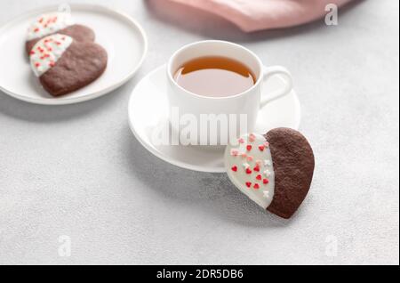 Dekoriert herzförmige Plätzchen und weiße Tasse Tee Stockfoto