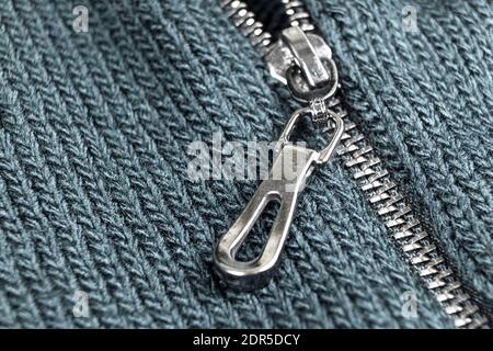 Makroaufnahme des Reißverschlusses auf blauem Wolle-Textur-Hintergrund mit Nähten. Horizontaler Hintergrund aus einer Nahaufnahme von Wollmaterial Stockfoto