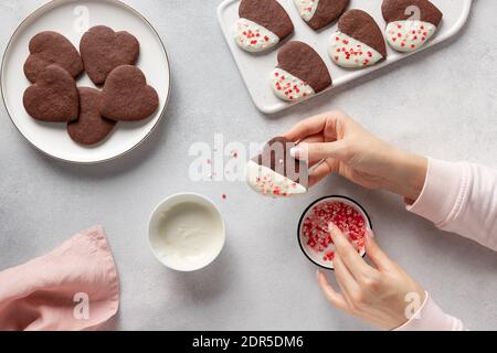 Nahaufnahme der weiblichen Hände, die hausgemachte herzförmige Kekse machen Stockfoto