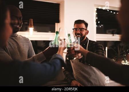 Diverse Gruppe lächelnder Freunde, die zusammen mit Getränken toasten Eine Küche vor einem Abendessen Party Stockfoto