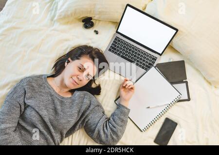 Junge Frau studieren im Bett Schreiben in Notebook arbeiten an Speicherplatz für Laptop-Kopien Stockfoto