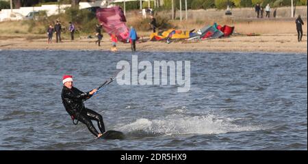 Sandbanks, Großbritannien. Dezember 2020. Ein Kitesurfer hält seinen Kopf warm mit einem weihnachtsmütze, wie er das Beste aus windigen Bedingungen am letzten Wochenende vor Weihnachten in Poole Hafen bei Sandbanks in Dorset macht. Kredit: Richard Crease/Alamy Live News Stockfoto