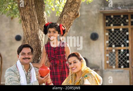 Ländliche indische Familie mit Tochter halten Sparschwein Stockfoto