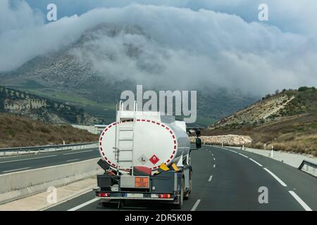 Kleine Tankwagen für zu Hause Kraftstofflieferung Fahren auf der Autobahn mit Blick auf Berge mit Wolken um ihn herum. Stockfoto