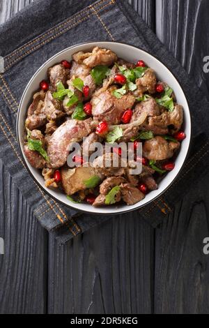 Köstliche Kuchmachi aus Hühnerfleisch mit Gewürzen, Zwiebeln und Granatapfel aus nächster Nähe in einer Schüssel auf dem Tisch. Vertikale Ansicht von oben Stockfoto