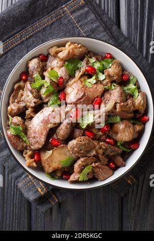 Kuchmachi georgischen Gericht aus Innereien mit Gewürzen, Zwiebeln und Granatapfel Nahaufnahme in einer Schüssel auf dem Tisch. Vertikale Draufsicht von oben Stockfoto