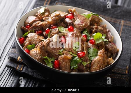 Gebratene Hühnerleber, Herzen und Muskelmagen mit Zwiebeln, Walnüssen und Granatapfel in einer Schüssel auf dem Tisch. Horizontal Stockfoto