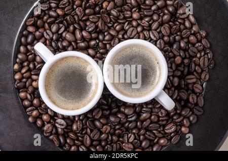 Gerösteter Kaffee Espressobohnen auf dunklem Hintergrund und Tassen mit Crema, close-up, flat lay, Hintergrund, Stillleben, heißes Getränk, Ich liebe Kaffee-Konzept Stockfoto
