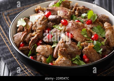 Hausgemachte Kuchmachi aus Hühnerleber, Herzen und Muskelmagen mit Zwiebeln, Walnüssen und Granatapfel Nahaufnahme in einer Schüssel auf dem Tisch. Horizontal Stockfoto