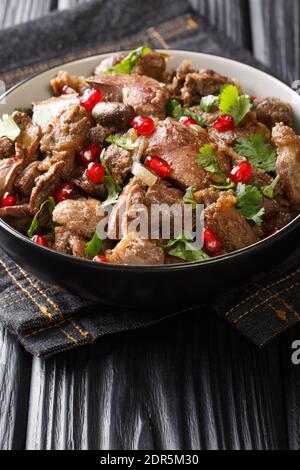 Köstliche Kuchmachi aus Hühnerfleisch mit Gewürzen, Zwiebeln und Granatapfel close-up in einer Schüssel auf dem Tisch. Vertikal Stockfoto