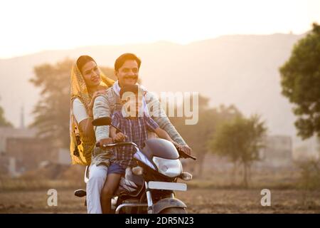 Glückliche ländliche indische Familie Reiten auf Motorrad Stockfoto