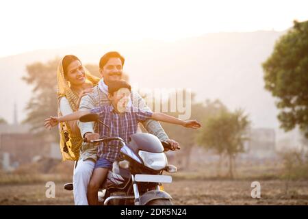 Glückliche ländliche indische Familie Reiten auf Motorrad Stockfoto