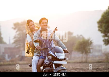 Glückliche ländliche indische Familie Reiten auf Motorrad Stockfoto