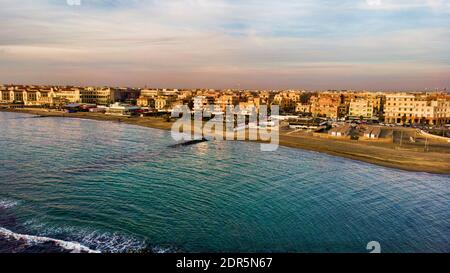 Sonnenuntergang Rom Luftaufnahme in Ostia Lido Strand über blauem Meer und braunem Sandstrand, schöne Küste und Promenade ein Wahrzeichen des touristischen und Stadtlebens Stockfoto