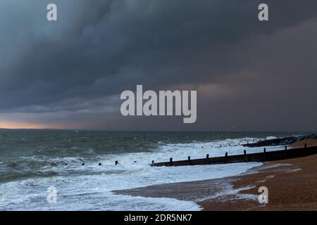 An der Südküste Englands sammeln sich Sturmwolken. Das raue Wetter nähert sich der Küste vom englischen Kanal. Die untergehende Sonne leuchtet weit weg. Stockfoto