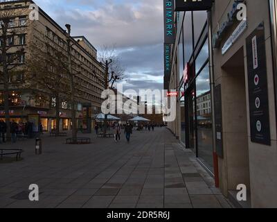 Menschen mit Gesichtsmasken kommen an geschlossenen Geschäften in der Einkaufsstraße Königstraße während der Covid-19-Sperre mit Bekleidungsgeschäften von Levi's und Primark vorbei. Stockfoto