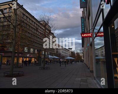 Menschen mit Gesichtsmasken gehen in der Einkaufsstraße Königstraße während der Covid-19-Sperre mit Weihnachtsdekoration an Bäumen vor den Geschäften von Primark. Stockfoto