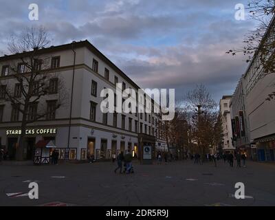 Menschen mit Gesichtsmasken gehen in der Einkaufsstraße Königstraße in der Innenstadt während der Covid-19-Sperre mit geschmückten Bäumen in der Weihnachtszeit. Stockfoto