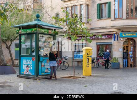 Llucmajor, Spanien; dezember 17 2020: Urbane Szene einer Person, die an einem Lotteriestand einkauft und Leute, die Schlange stehen, um in ein Tabakgeschäft einzusteigen. Neuer Normalwert Stockfoto