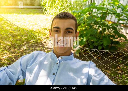 Selfie-Porträt eines schönen jungen lächelnden Kerl liegt in Eine Hängematte an einem sonnigen Sommertag Stockfoto