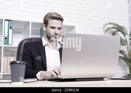 Konzentrierter Broker. Wirtschaft Rezession und Erholung. Finanzexperte Mann arbeiten mit Laptop trinken Kaffee. Börsenkonzept. Finanzielle Investitionen Kryptowährung. Finanzdirektorbüro. Stockfoto