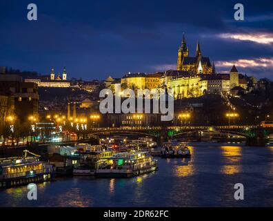 Atemberaubende Aussicht auf die Prager Altstadt in der Abenddämmerung, mit Burg und Kathedrale im Hintergrund und Fluss im Vordergrund Stockfoto