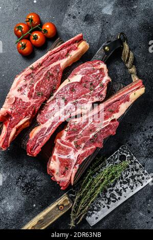 Auswahl an Rohschnitten Rinderfleisch Steaks auf den Knochen. Schwarzer Hintergrund. Draufsicht. Stockfoto