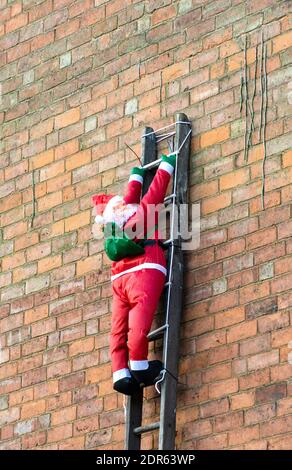 Vater Weihnachtsfigur Klettern eine Leiter Stockfoto