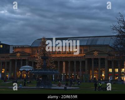 Menschen entspannen auf dem beliebten Schlossplatz in der Innenstadt vor dem historischen Gebäude Königsbau in der Weihnachtszeit mit Dekorationen. Stockfoto