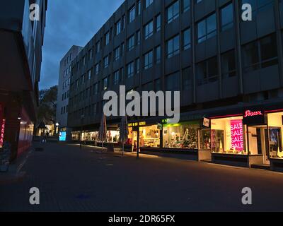 Verlassene Einkaufsstraße im Stadtzentrum mit einer Reihe von geschlossenen Geschäften während der Covid-19-Sperre und beleuchteten Schaufenstern am Abend in der Weihnachtszeit. Stockfoto