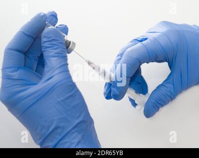 Hände aus blauem Gummi Handschuhe halten medizinische Spritze und Fläschchen Nahaufnahme auf weißem Hintergrund Stockfoto