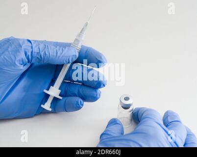 Hände aus blauem Gummi Handschuhe halten medizinische Spritze und Fläschchen Nahaufnahme auf weißem Hintergrund Stockfoto