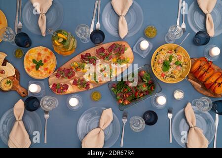 Übersicht der servierten Festtafel mit hausgemachtem vegetarischen Salat, Kuchen, Sandwiches, Pasta, gebackenen Kürbisscheiben, Limonade und anderen Dingen Stockfoto