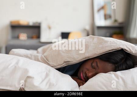 Minimal top view Portrait der jungen afroamerikanischen Frau schlafen unter Weiße Baumwolle Decke genießen Komfort von warmen Bett Stockfoto