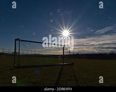 Fußballtor mit zerrissenem Netz auf dem Fußballplatz in der Nähe des kleinen ländlichen Dorfes Breitenholz, Ammerbuch, Deutschland am sonnigen Wintertag mit strahlender Sonne. Stockfoto