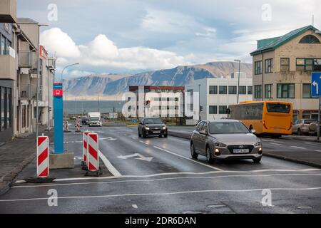 Snorraraut Street In Reykjavík Mit Videy Island Im Hintergrund Öffentliche Busse Und Privatwagen, Das Meer In Kollafjordur Bay Stockfoto